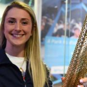 Dame Laura Kenny holding a London 2012 Olympic torch